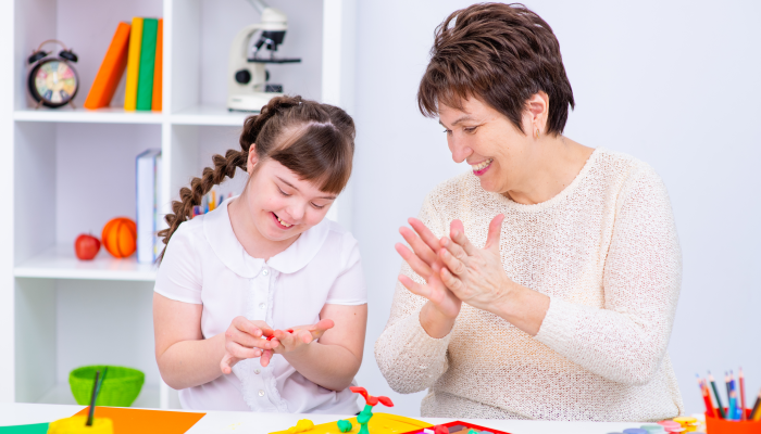 Girl with Down Syndrome works with her teacher at home.