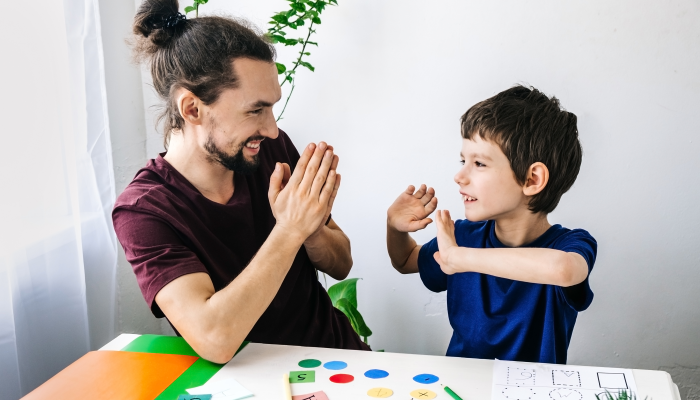 Happy autism boy during therapy with school counselor, learning and having fun together.