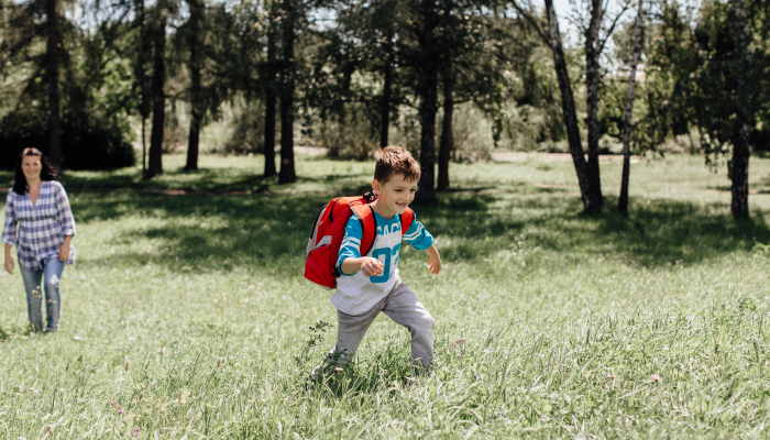 Happy schoolboy on way to school running away from mother.