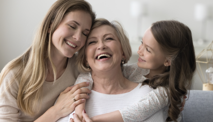 Joyful grandkid girl and adult daughter woman hugging happy excited grandma.