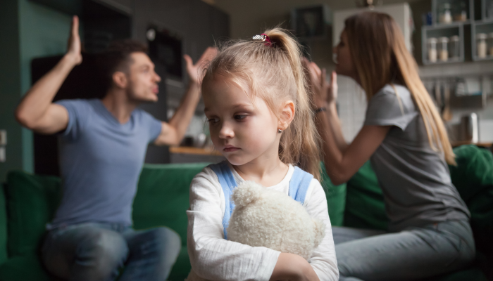 Kid daughter feels upset while parents fighting at background.