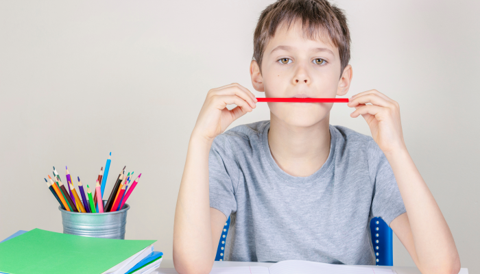 Kid doing homework at the table and thinking or dreaming.