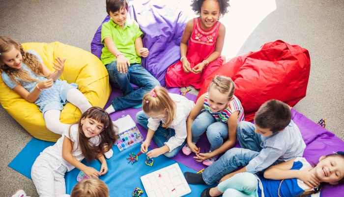 Large Group of happy smiling kids sitting together and playing indoor.