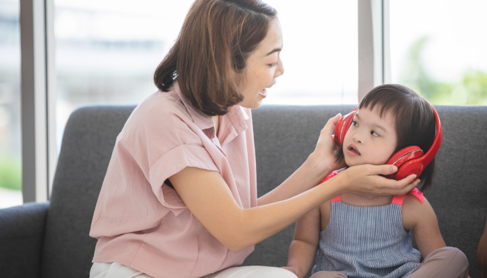 Little girl with learning disabilities or the group of dow syndrome is listening music from headphone.