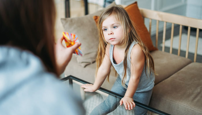 Little girl with specialist on psychological educational game, metaphorical associative cards.