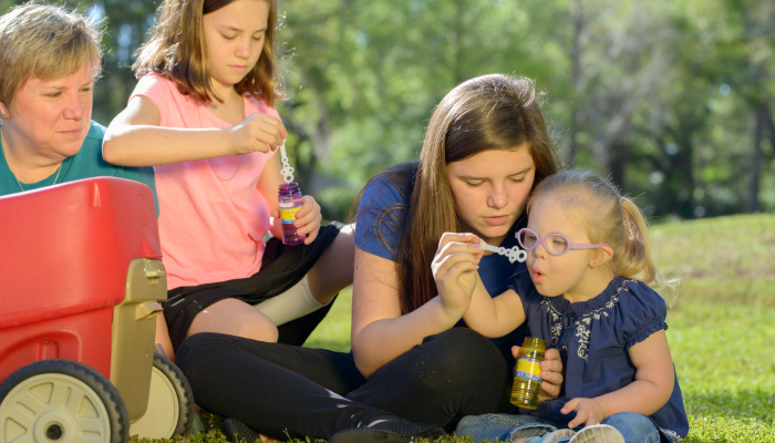 Mother and Daughters Blow Bubbles, Child with Down Syndrome.