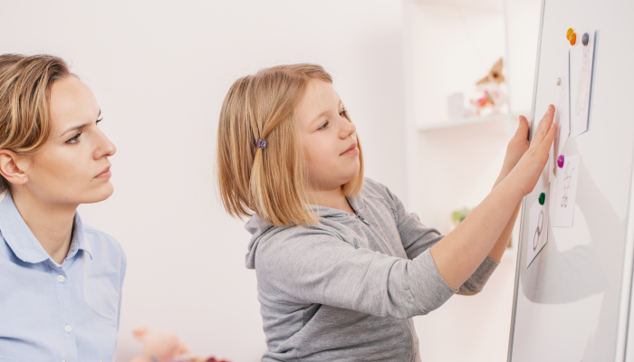 Smiling girl doing exercises during meeting with concentrated psychotherapist.