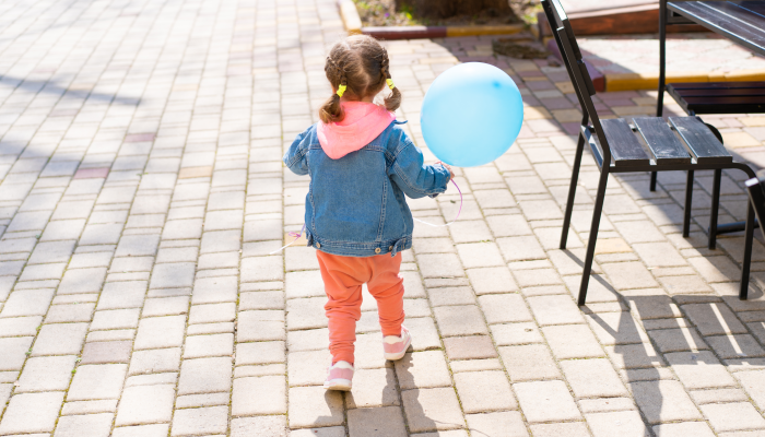 The little girl runs away from her parents with an inflatable ball in their hands.