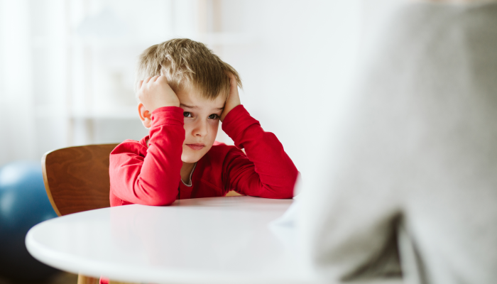 Tired young boy sitting by the desk.