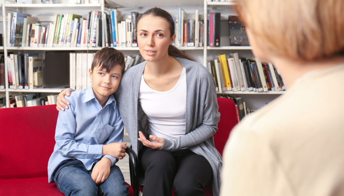 Young mother and little boy on meeting with teacher at school.