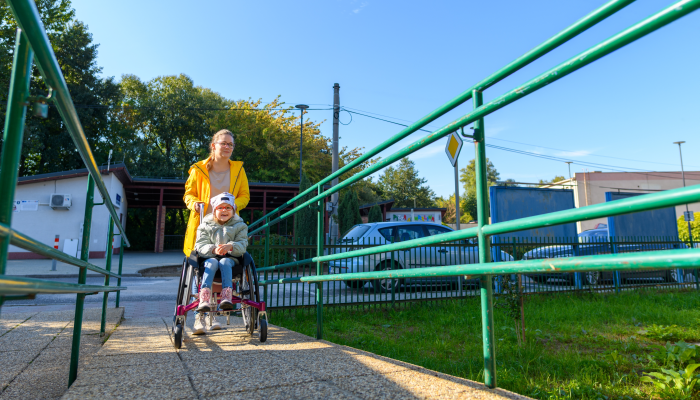 Young mother pushing a wheelchair with her daughter.