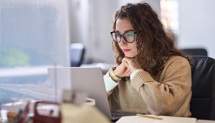 Young serious busy professional business woman employee or student using laptop.