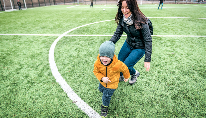 the boy runs away from the girl, mother over green grass.