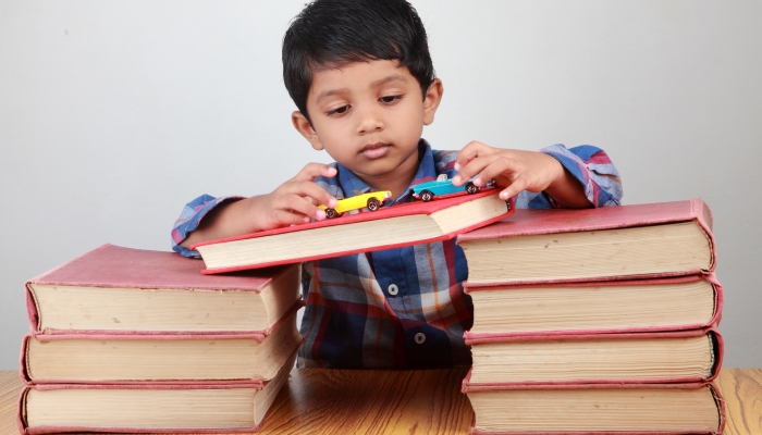 A small boy plays with fat books.