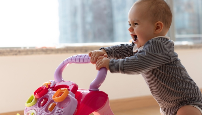 Baby girl pushing a toy walker.