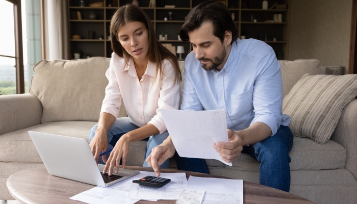 Concentrated young family couple calculating expenditures.