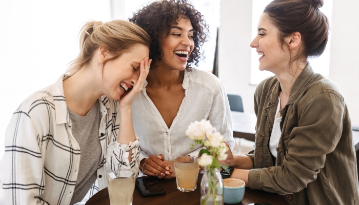 Happy young women friends having coffee break while relaxing at the cafe indoors.