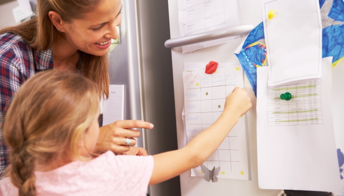 Mother And Daughter Putting Star On Reward Chart.