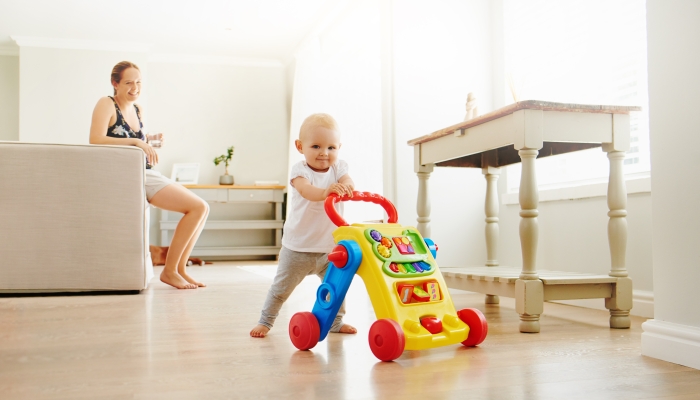 Portrait of an adorable baby girl playing with a toy walker at home.