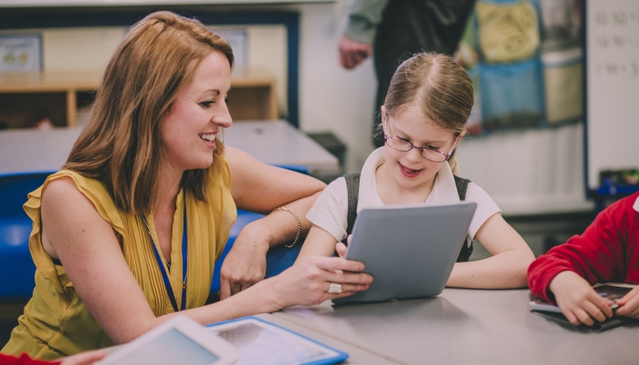 Teacher is helping one of her primary school students in the classroom.