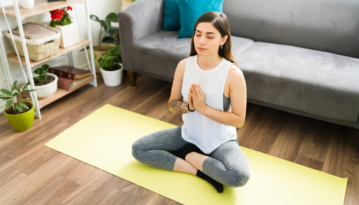 Woman in her 20s doing a praying yoga pose with her eyes closed.