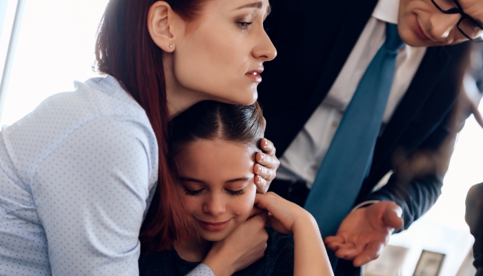 Young red-haired woman hugging crying girl.
