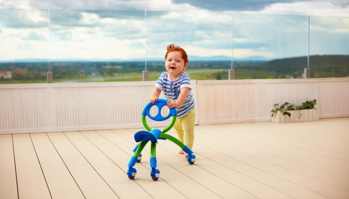 happy toddler baby boy pushing pushing go cart, outdoors.