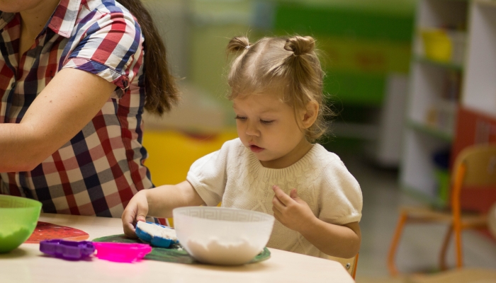 little girl playing with kinetic sand and forms.