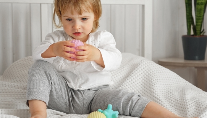 Cute baby girl playing tactile knobby balls.